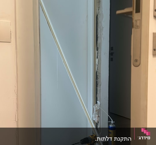 דלת לבנה בתהליך התקנה עם כלים וחומרים